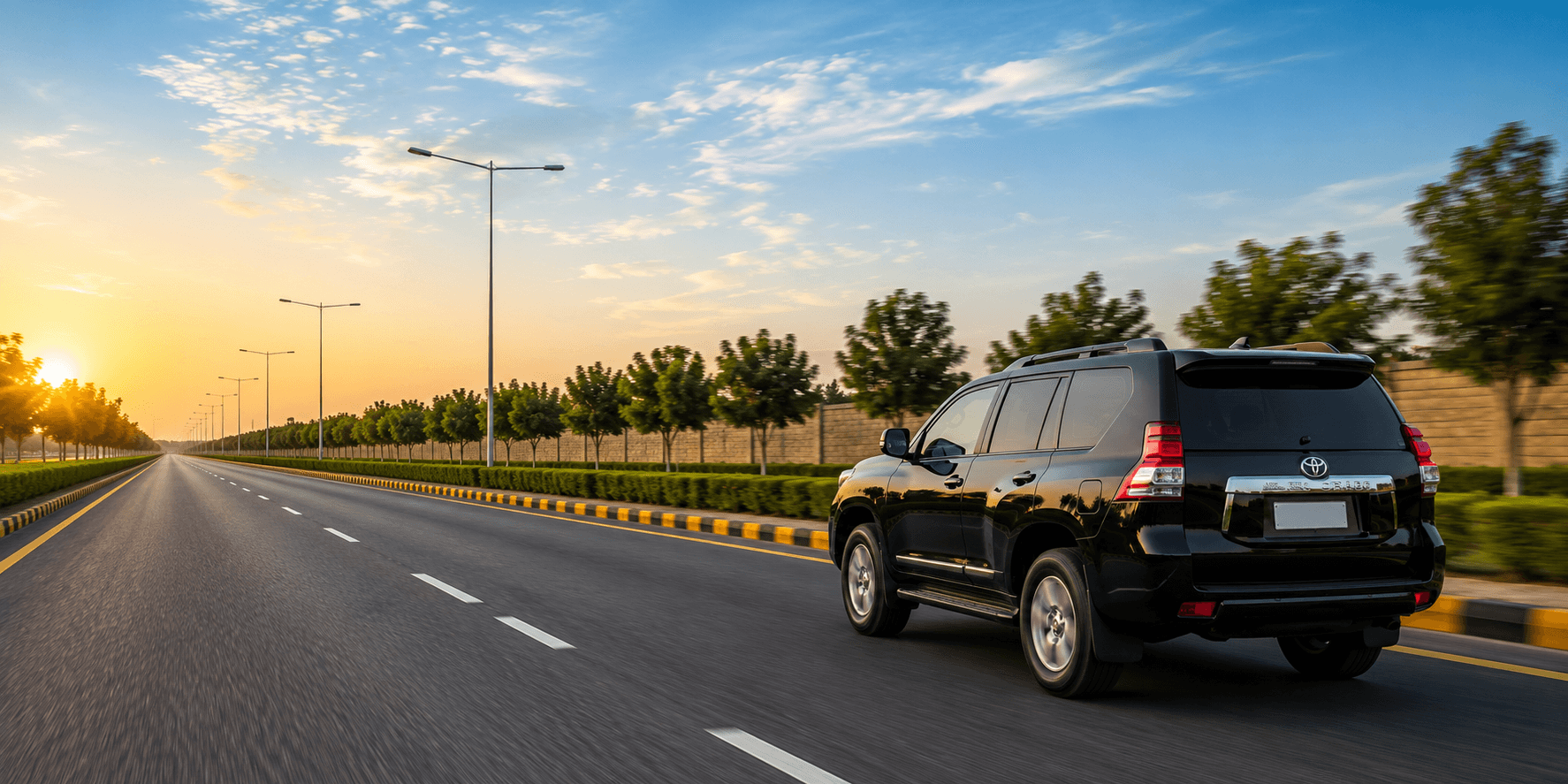 A black SUV on an open road at sunrise